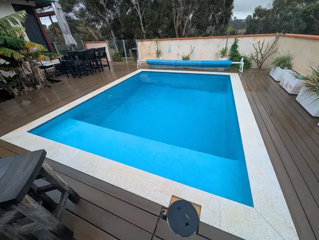 Close view of a bright blue pool with granite coping