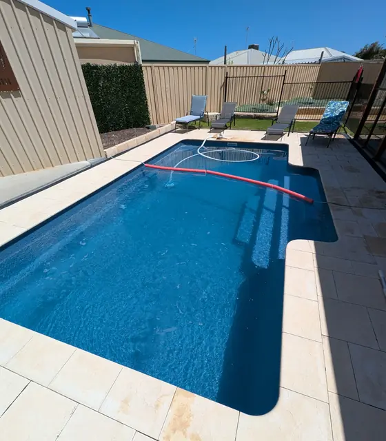 Blue pool with limestone pavers and sun loungers