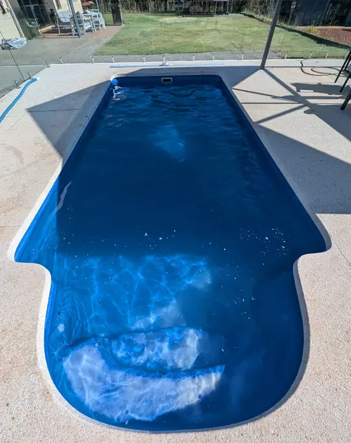 Deep blue pool with rounded entry steps and a glass fence