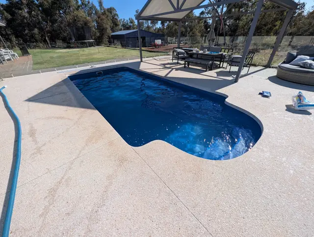 The same pool beside an outdoor dining pergola