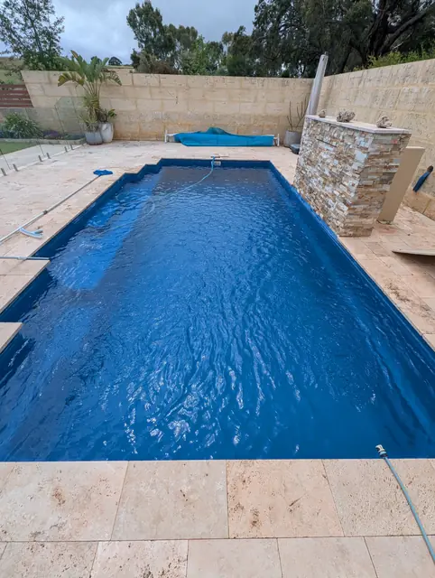 Deep blue pool beside a stacked stone water feature
